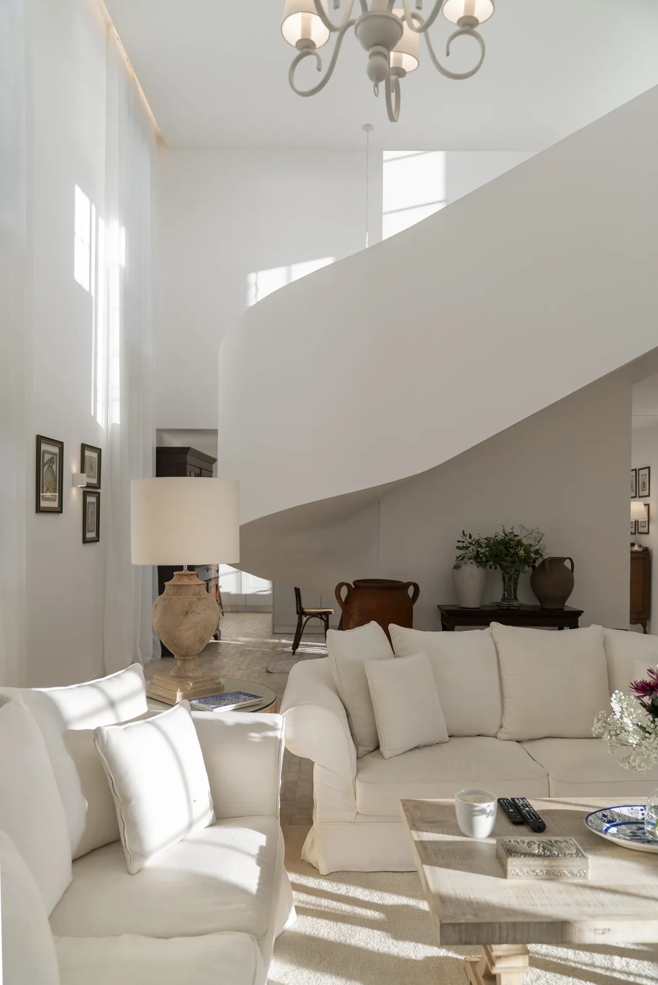 Sala de pé-direito duplo com escada curva, na Casa no Paul do Mar.