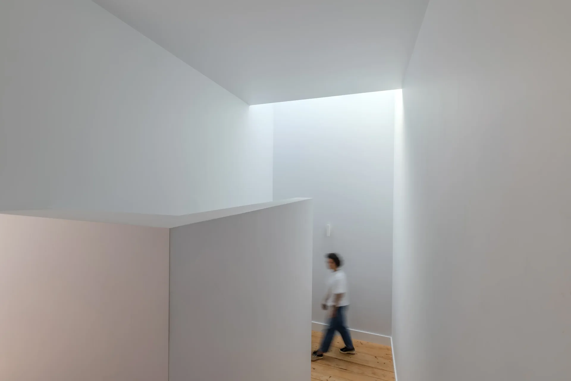 Espaço interior branco com luz rasante, na Casa na Casa Branca.