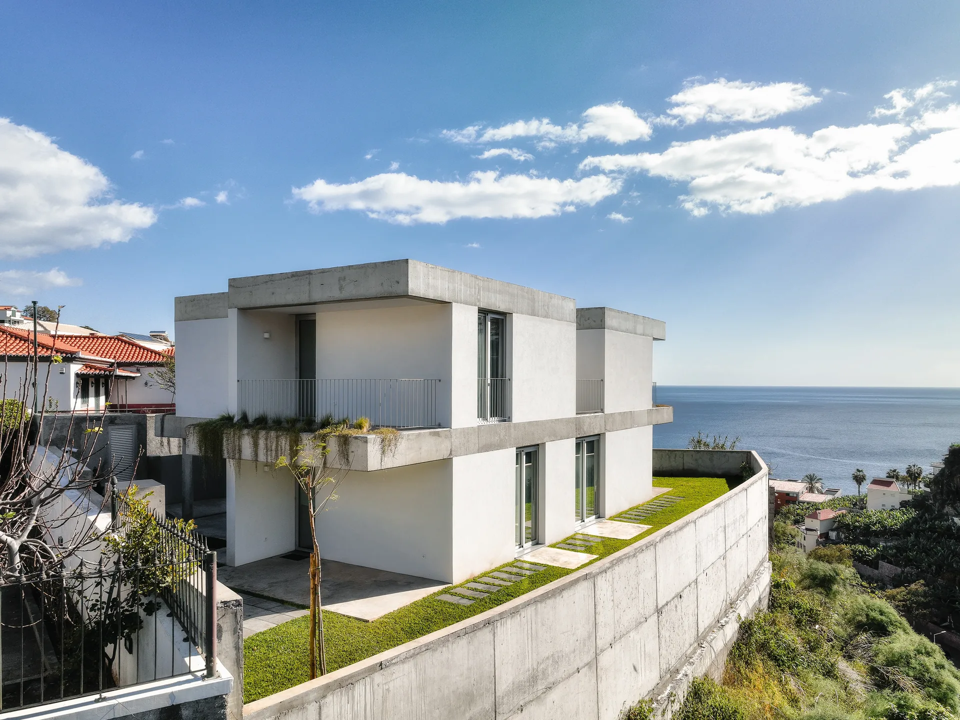 Casa no Serrado da Adega sobre a encosta de Câmara de Lobos, com o mar em fundo.