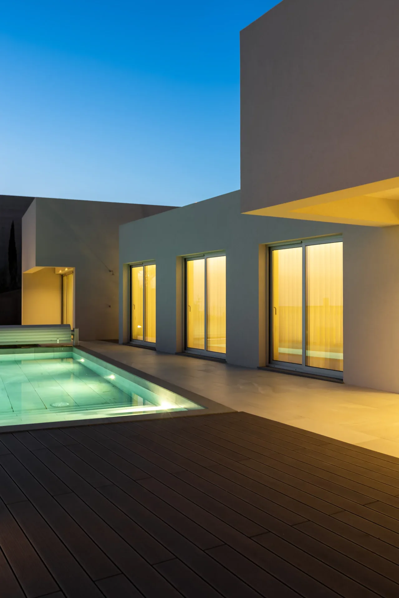 Piscina e sala iluminada ao anoitecer, na fachada sul da Casa nos Saltos.
