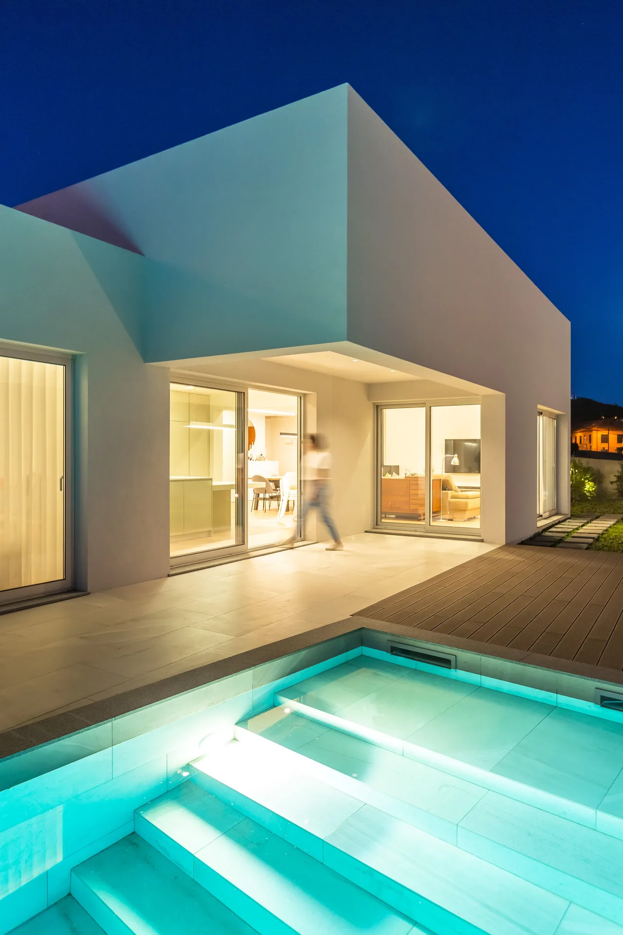 Piscina iluminada e interior aceso ao anoitecer, na Casa nos Saltos.